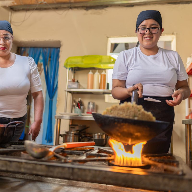 Peruvian cook preparing Chaufa rice in a commercial kitchen next to a colleague
