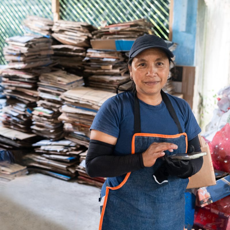 Portrait of a focused Hispanic woman documenting recycling data on her phone, displaying commitment to eco-conscious practices